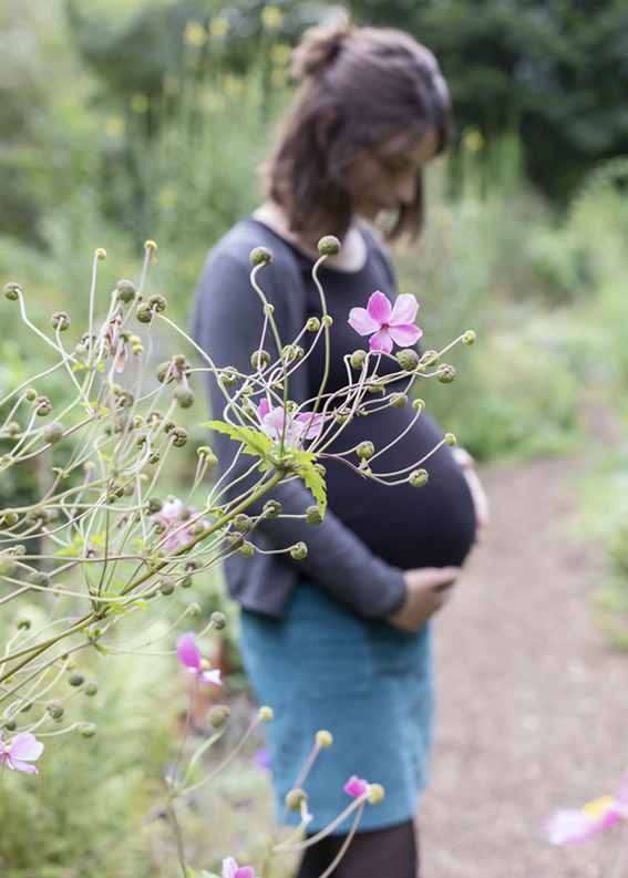 schwangere mit herbstanemone im vordergrund